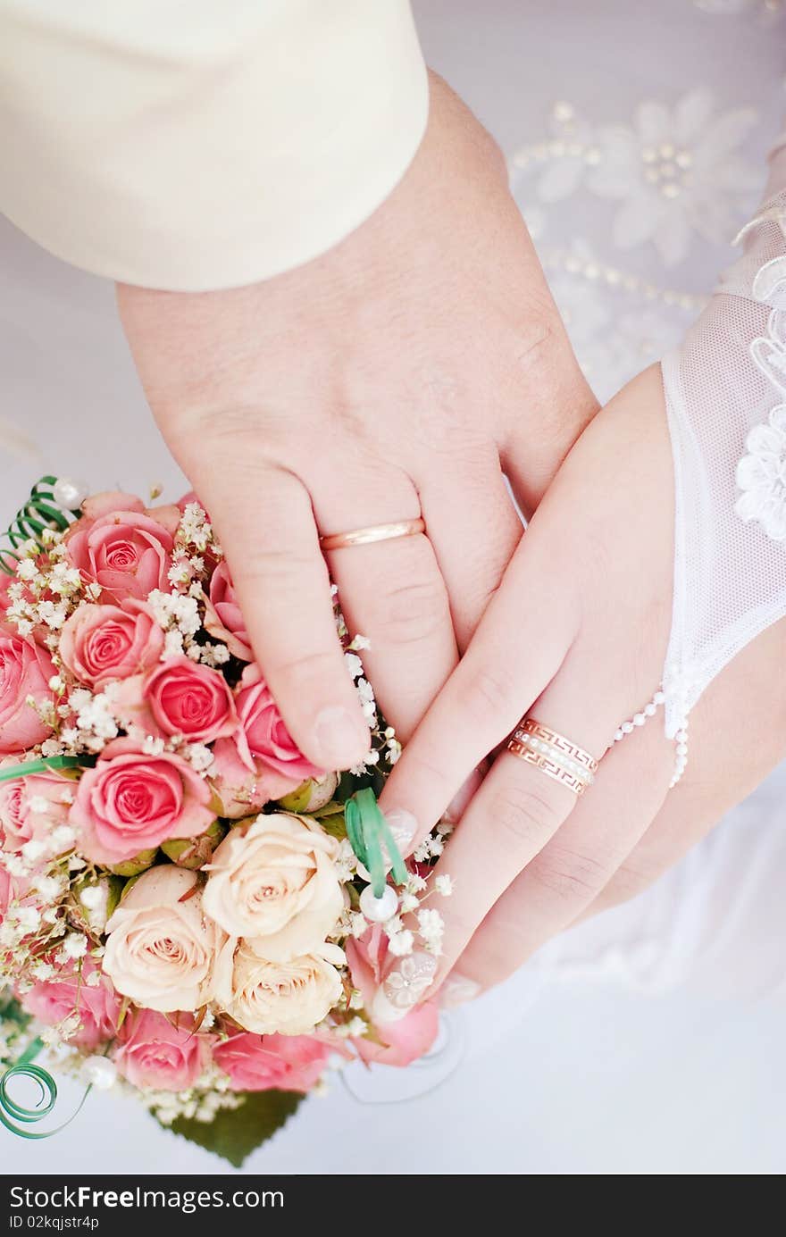 Wedding rings on hands with a bouquet