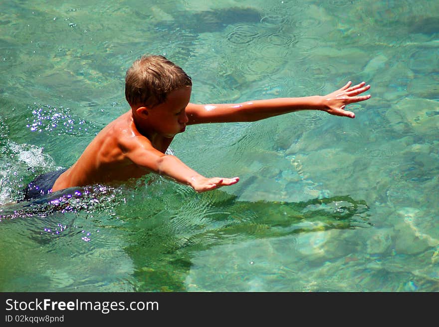 A boy is learning to swim in adriatic water