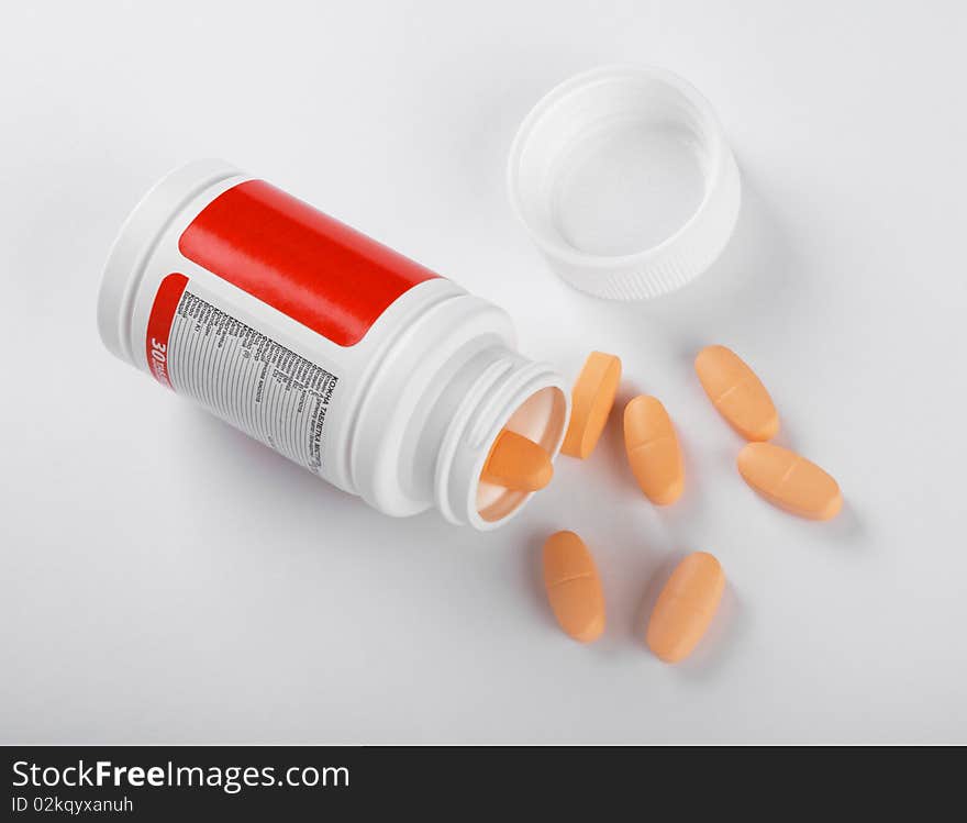 Pot of yellow tablets on a white background