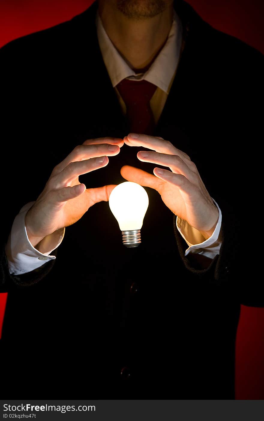 Businessman holding a light bulb on red background. Businessman holding a light bulb on red background