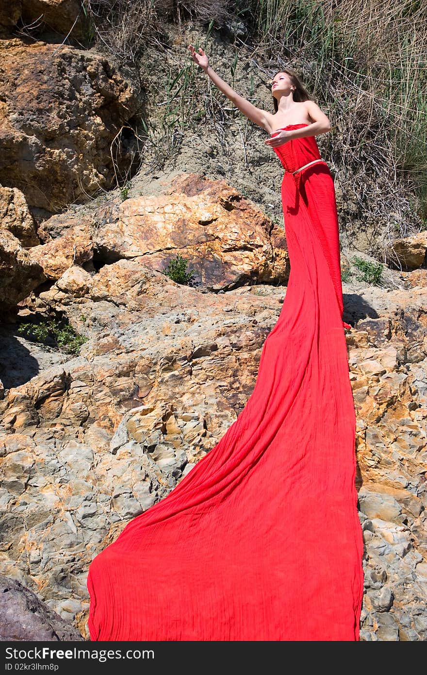 Woman in red dress from material and rocks