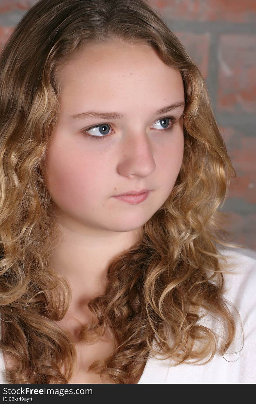 Beautiful teen with curly hair against a brick wall background