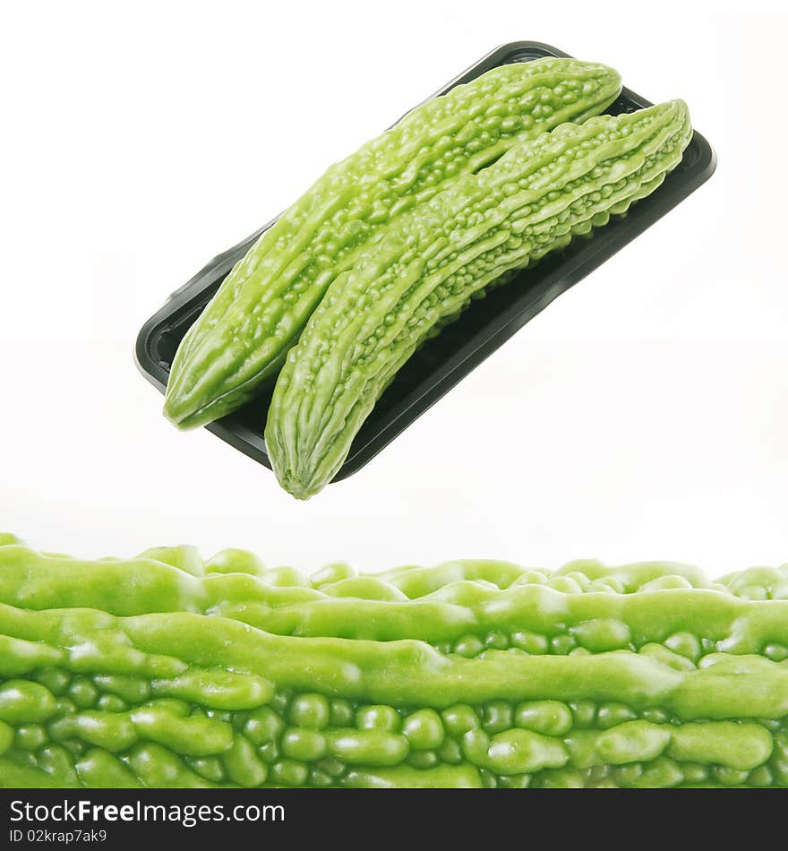 Close up of a fresh bitter melon and two bitter melon in dark box.(on white)