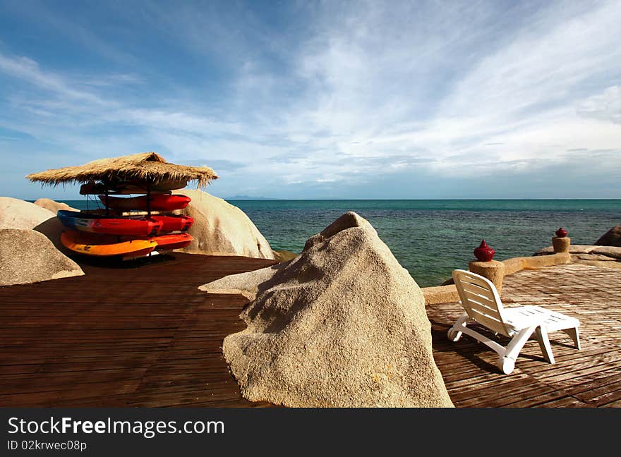 A waterfront resort' sundeck with loungers and canoes on the coral reef in Koh Tao, Thailand. A waterfront resort' sundeck with loungers and canoes on the coral reef in Koh Tao, Thailand.