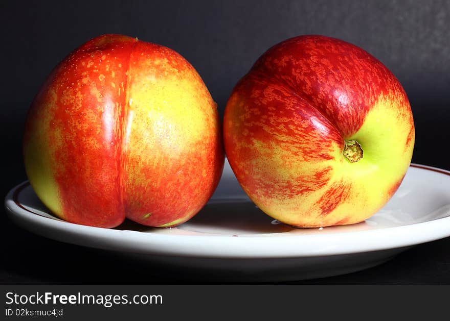 Two nectarines on black background.