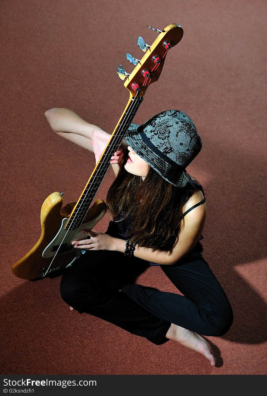 Young pretty woman with guitare sitting on the floor