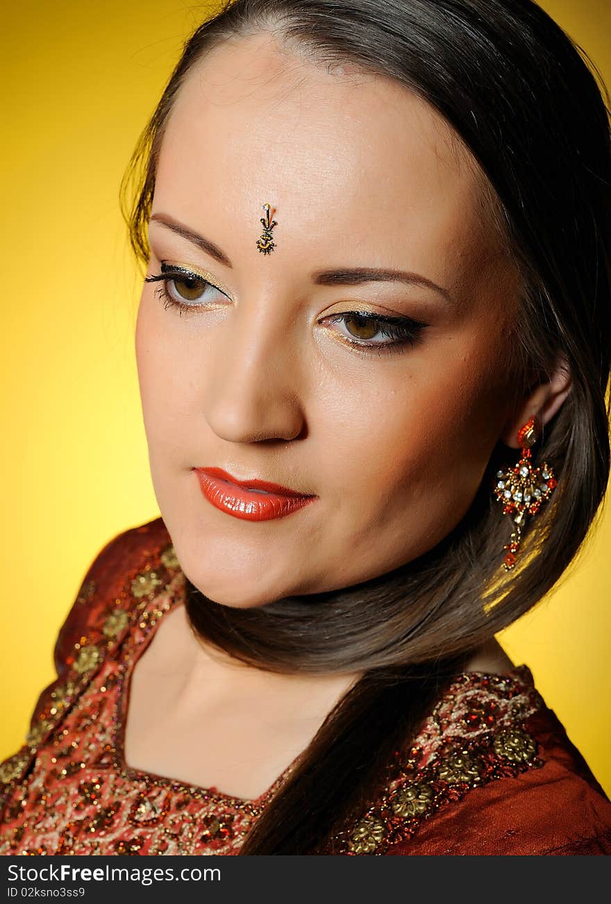 Young beautiful woman in indian traditional jewellary, bindi and sari dress. yellow background. Young beautiful woman in indian traditional jewellary, bindi and sari dress. yellow background