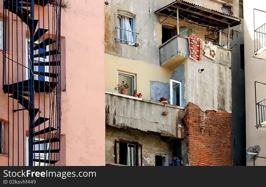 Underprivileged Areas Of City. Closeup of old building with spiral staircase flowerpots and small balcony