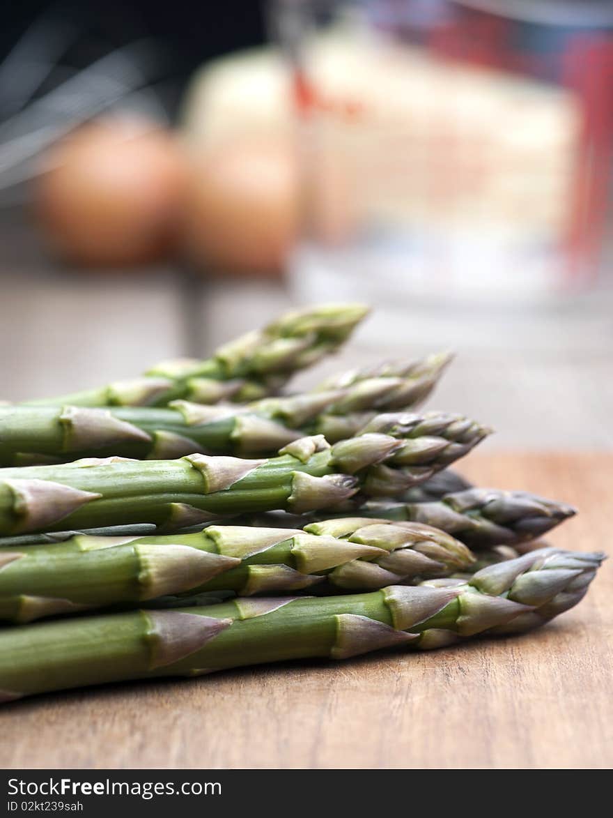 Fresh Asparagus Laid Out On A Wooden Chopping Board, With Ingredients For Hollandaise Sauce In The Background