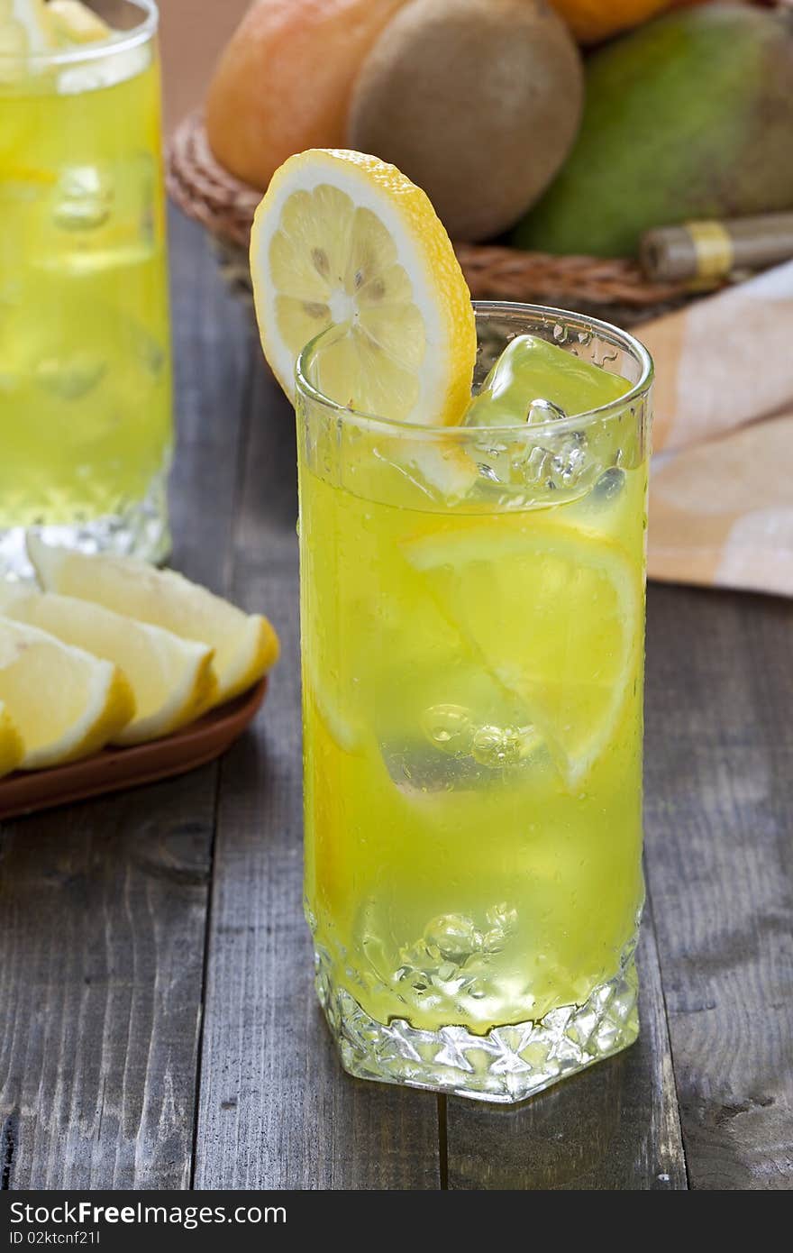 Glass of cold lemon cocktail with ice cubes on wooden table top. Glass of cold lemon cocktail with ice cubes on wooden table top