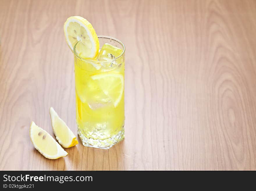 Glass of cold lemon beverage with slices of lemon fruit on wooden table top. Glass of cold lemon beverage with slices of lemon fruit on wooden table top