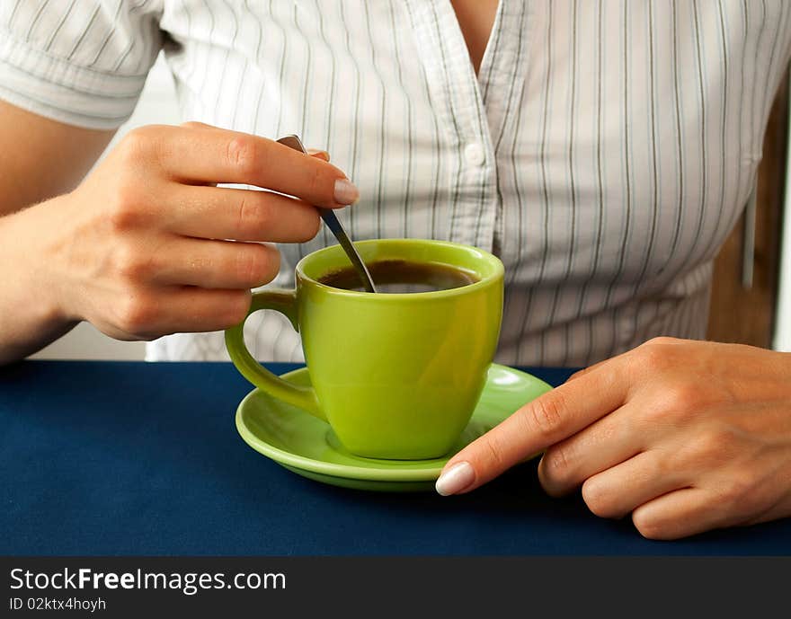 A girl sitting at a table drinking tea.