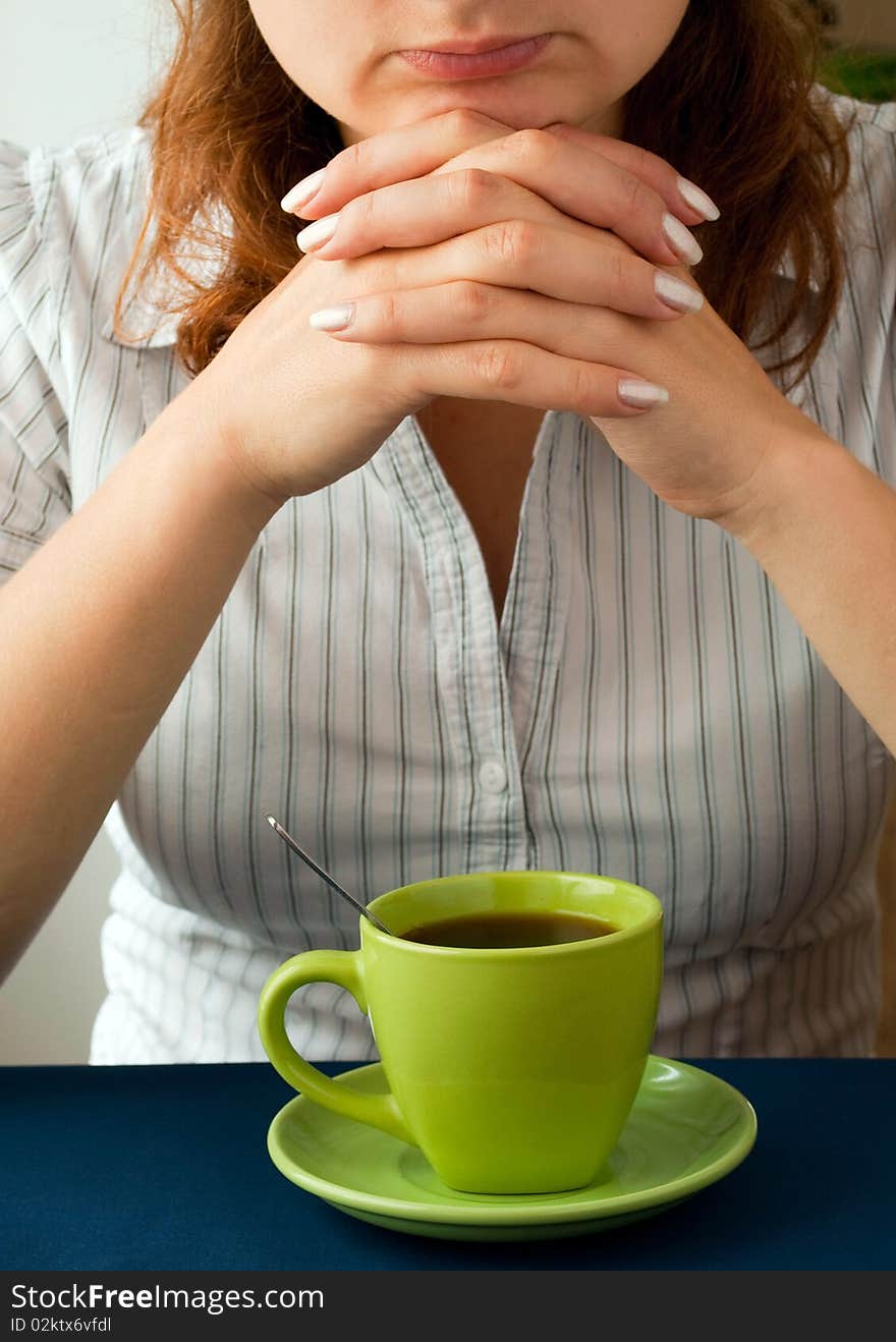 A girl sitting at a table drinking tea.