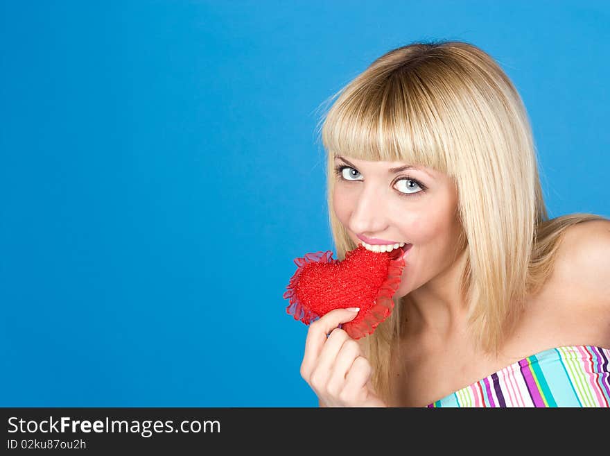 Attractive woman biting a red heart over blue