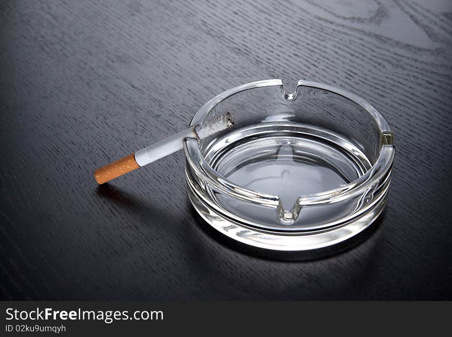 Cigarette and ashtray on black table