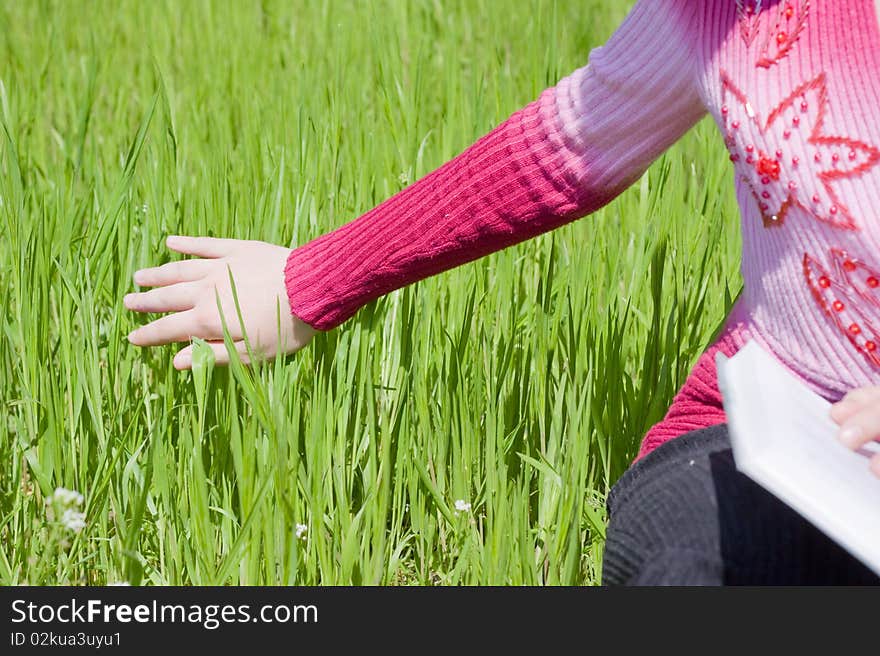 Girls hand over green grass. Girls hand over green grass