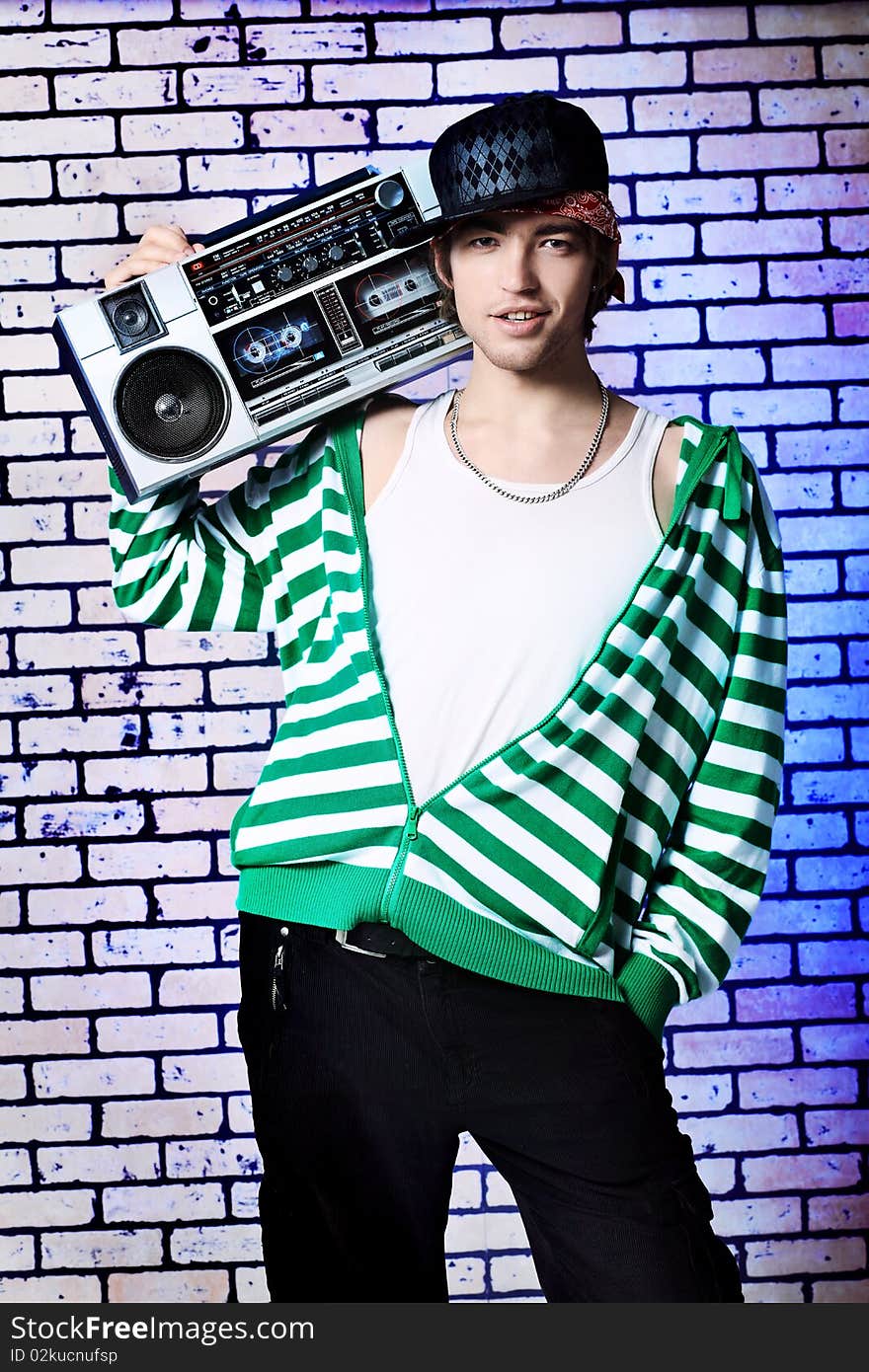 Trendy young man posing  against a brick wall with tape recorder. Trendy young man posing  against a brick wall with tape recorder.