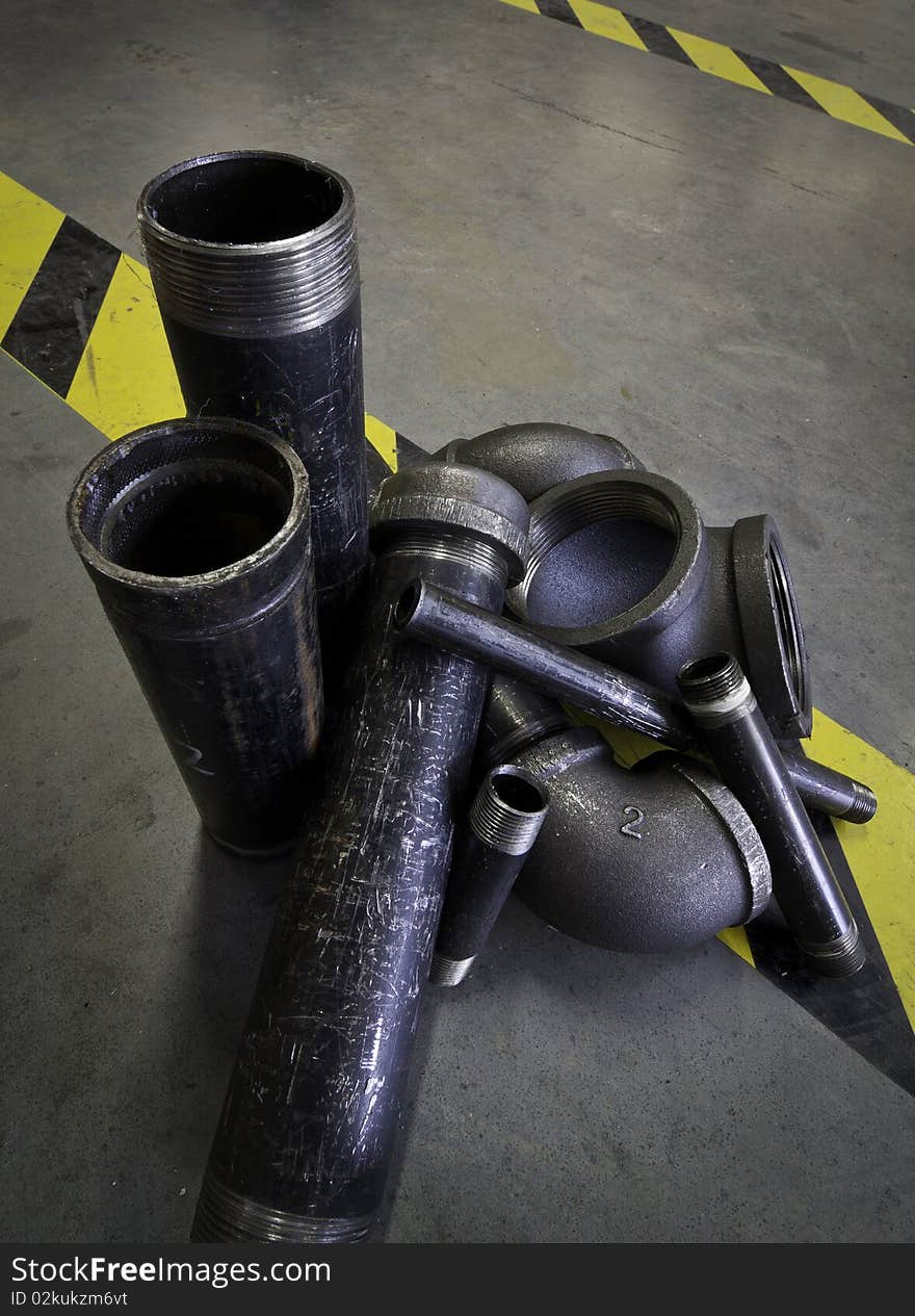 Grouping of assorted pipe pieces arranged on the factory floor. Grouping of assorted pipe pieces arranged on the factory floor