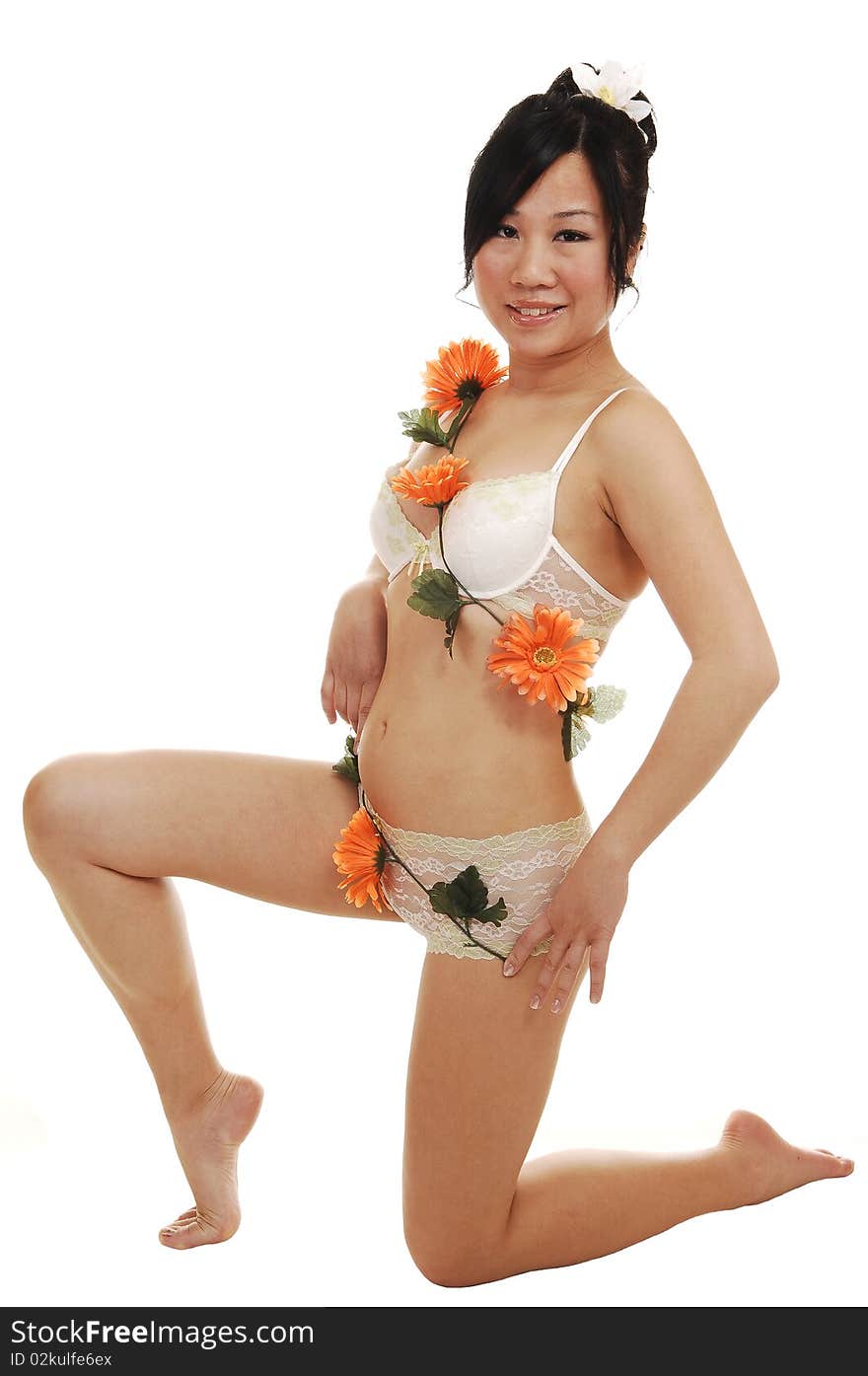 A young slime Asian woman kneeling in the studio in lingerie and some nice orange flowers around her body, for white background. A young slime Asian woman kneeling in the studio in lingerie and some nice orange flowers around her body, for white background.