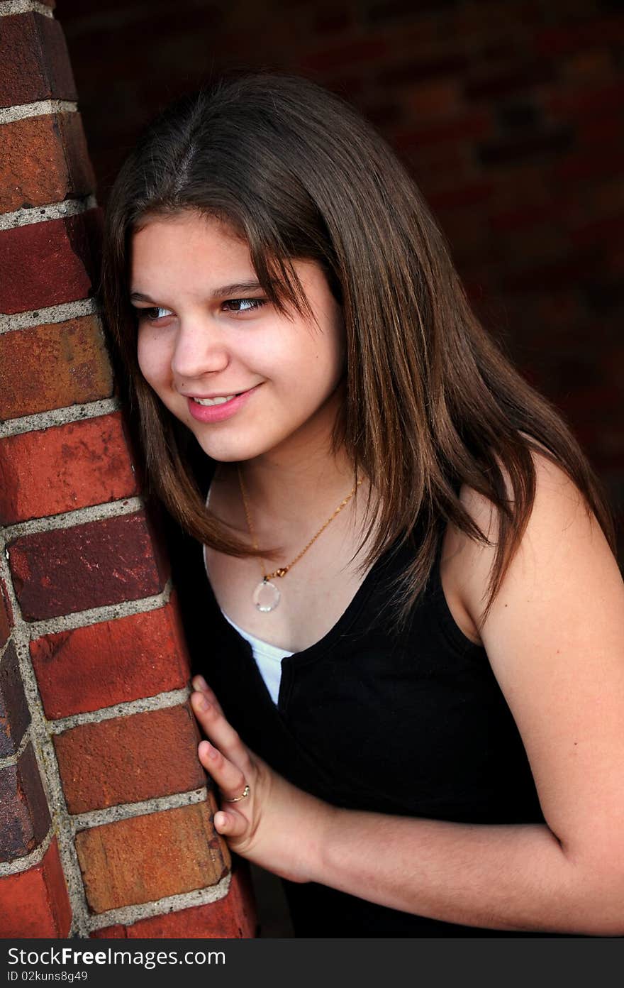 Closeup of a happy young teen looking into the distance from behind a brick doorway. Closeup of a happy young teen looking into the distance from behind a brick doorway.