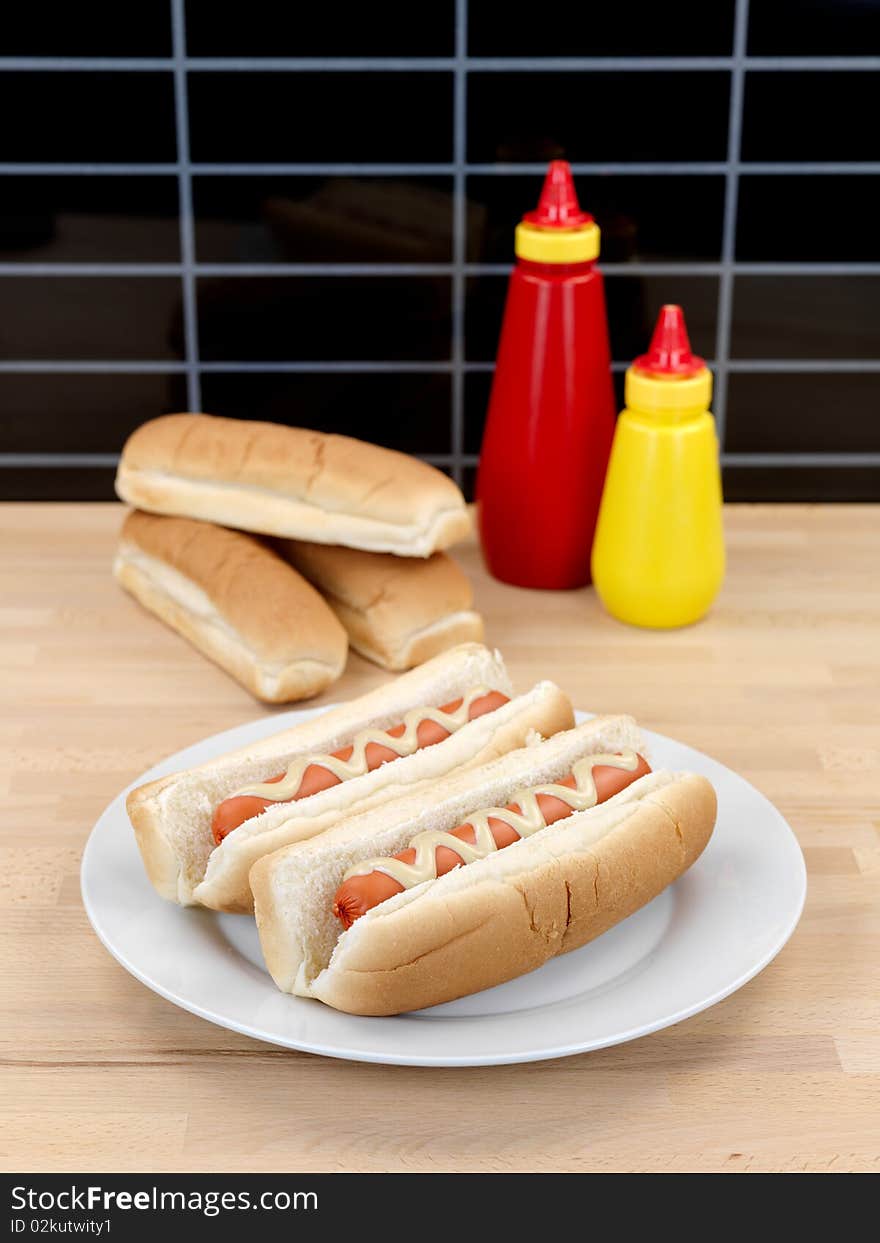 A hotdog with mustard sauce on a kitchen bench. A hotdog with mustard sauce on a kitchen bench