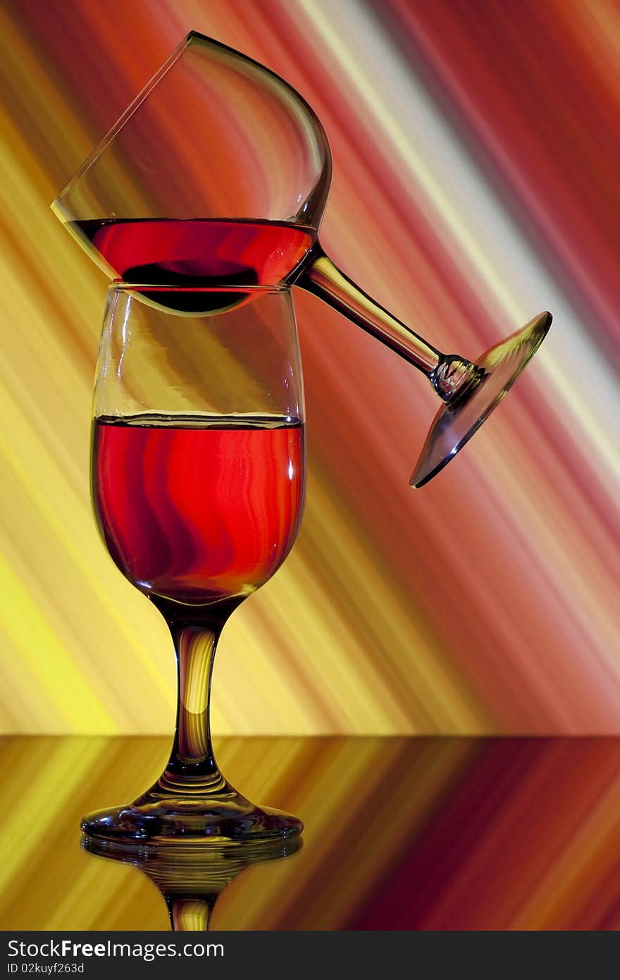 One wine glass balanced on another with colorful background. One wine glass balanced on another with colorful background