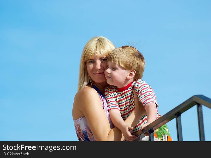 Mum with the small son on hands on a background of the dark blue sky. Mum with the small son on hands on a background of the dark blue sky