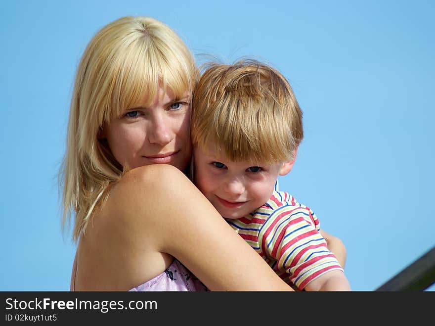 Mum with the small son on hands on a background of the dark blue sky. Mum with the small son on hands on a background of the dark blue sky