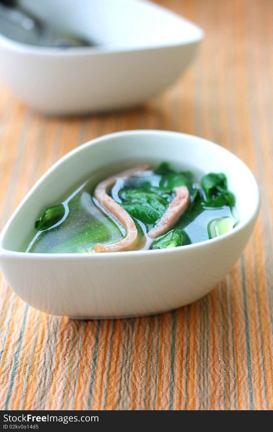 A boiling pot of vegetable soup on top of the stove. Focus across the middle of image.