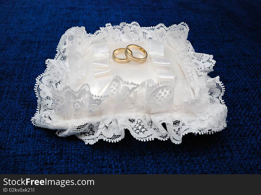 Gold wedding rings on a satiny pillow