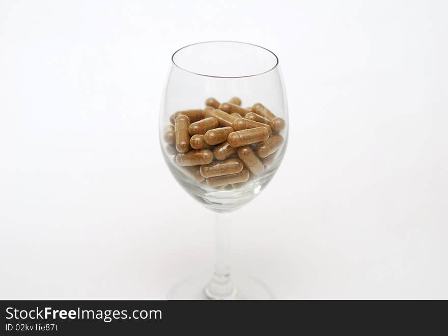 Medicine capsules in wine glass. For drug addiction, healthy eating and lifestyle, dieting and slimming, and healthcare concepts. Medicine capsules in wine glass. For drug addiction, healthy eating and lifestyle, dieting and slimming, and healthcare concepts.