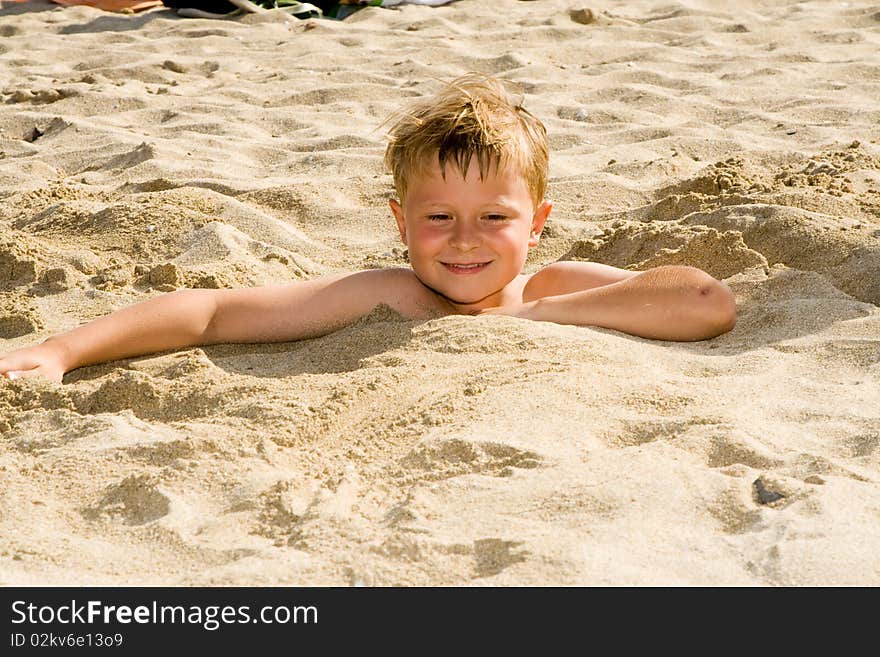 Child at the beach is covered by sand