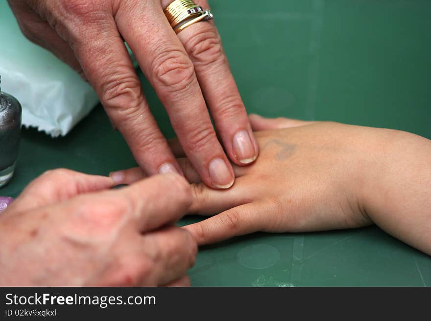 A mother painting her daughters fingernails. A mother painting her daughters fingernails