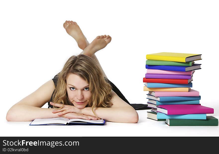 Smiling sweet girl lying on floor reading a book next to stack of colorful books, isolated on white background. Smiling sweet girl lying on floor reading a book next to stack of colorful books, isolated on white background.