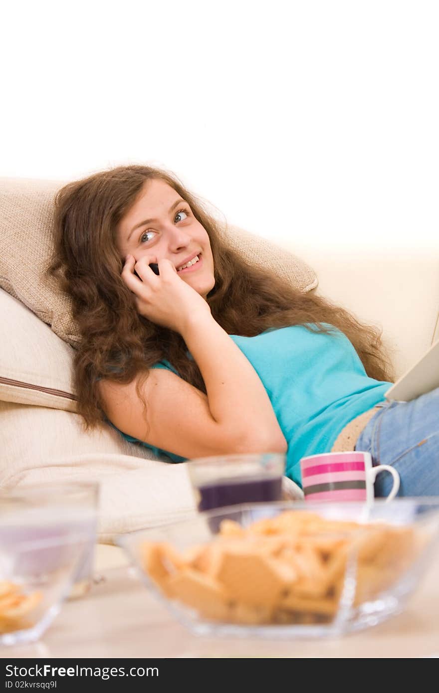 Attractive young girl lying on sofa and talking on phone