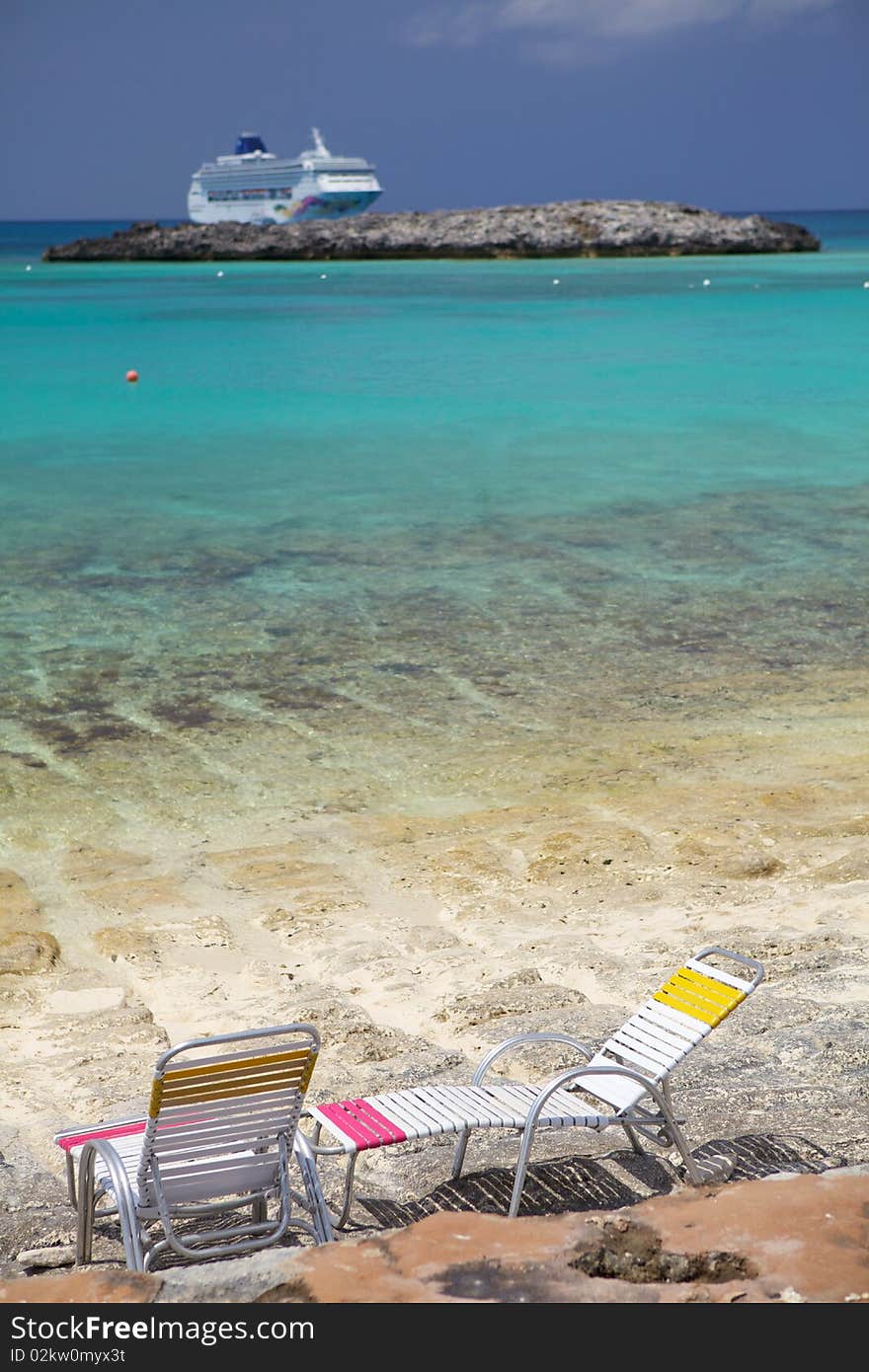 Two chairs on the water looking a cruise ship. Two chairs on the water looking a cruise ship