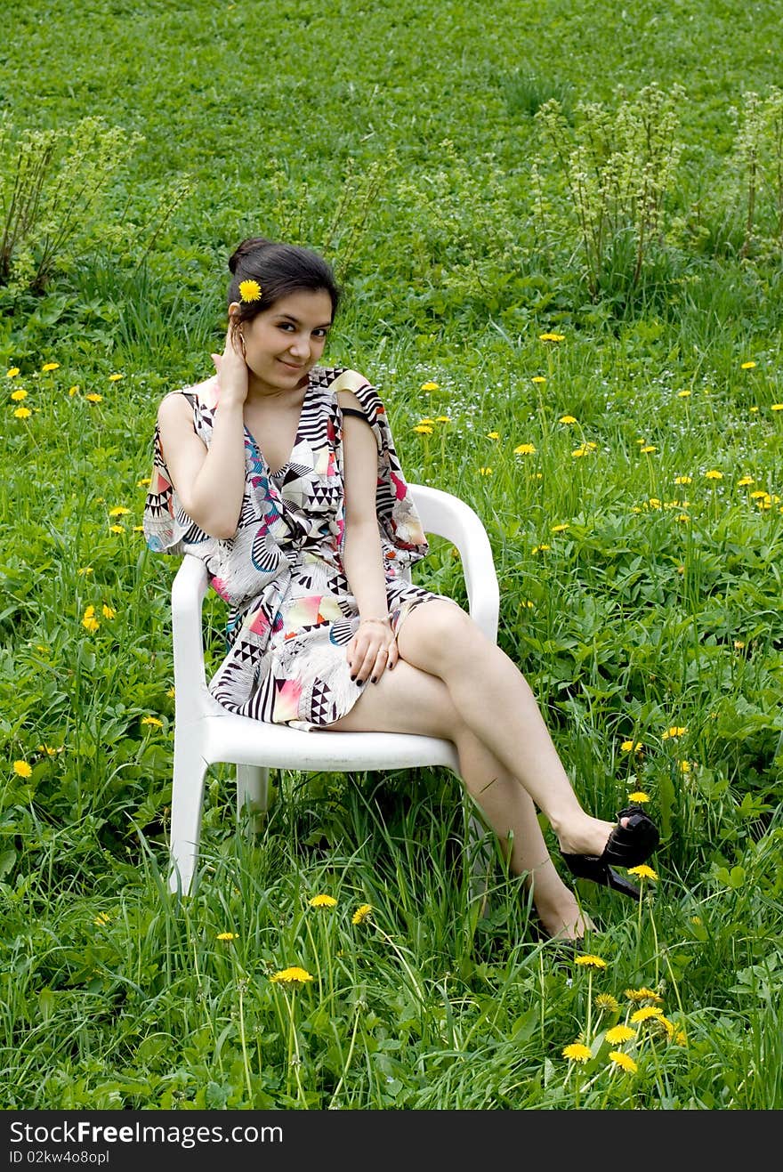 Girl resting in a chair among dandelions