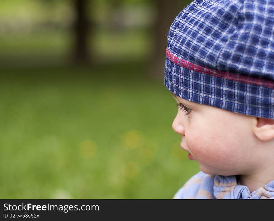 Profile portrait of a little child outdoors  on summer or spring day, green grass in the background. Profile portrait of a little child outdoors  on summer or spring day, green grass in the background.