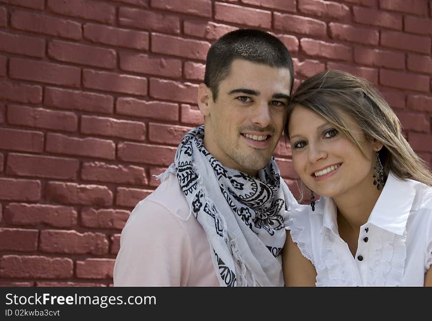 Attractive couple smile in front of a brick wall