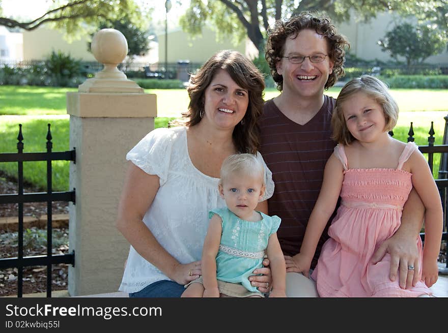 Family smiles and sits on a park bench. Family smiles and sits on a park bench