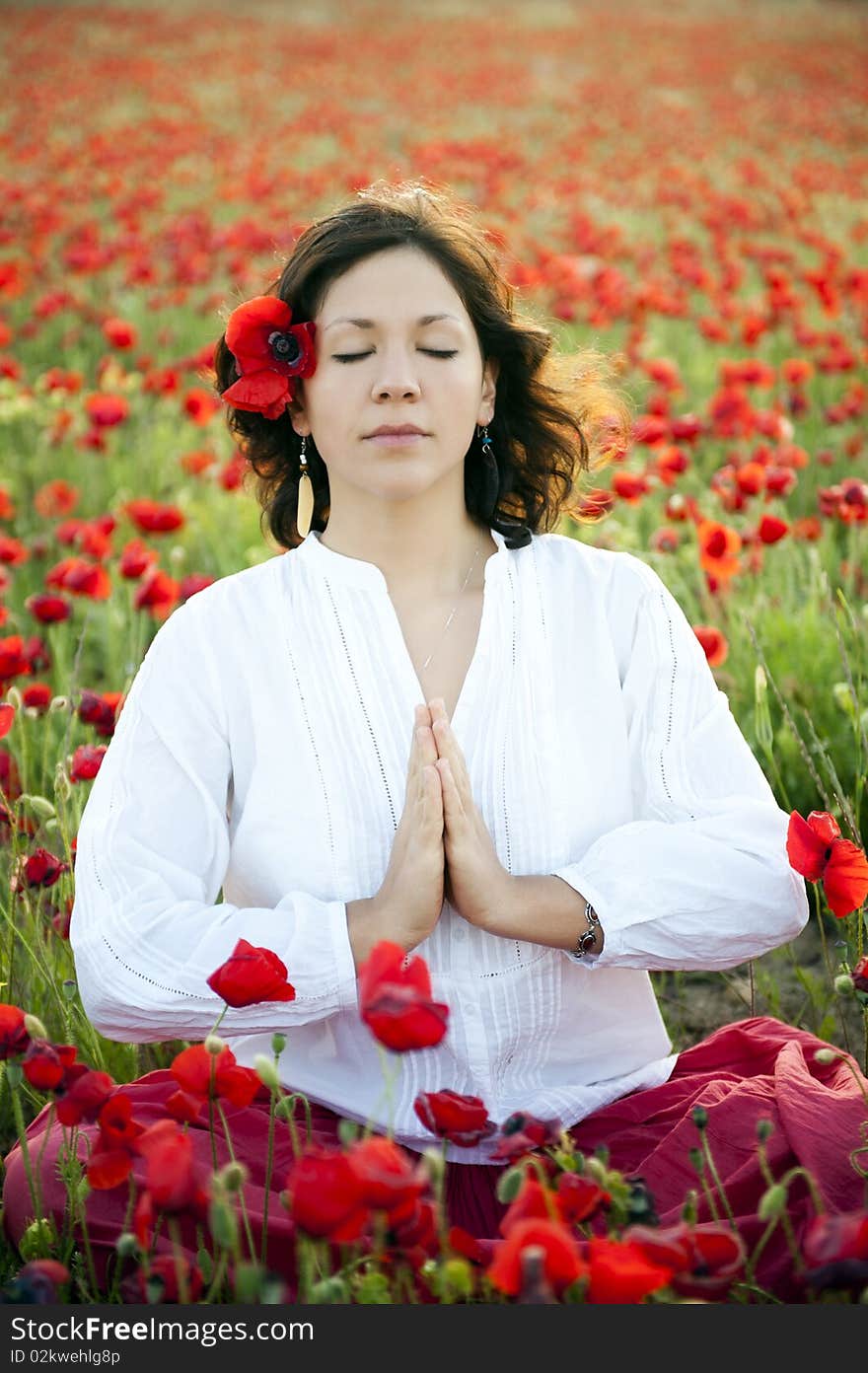 Young beautiful woman meditating in spring field