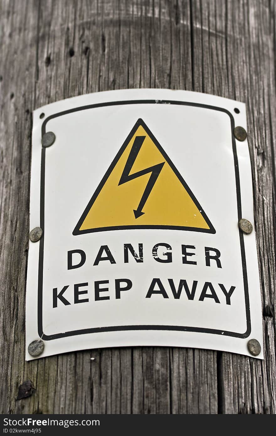 A danger electricity sign on a wooden pole. A danger electricity sign on a wooden pole