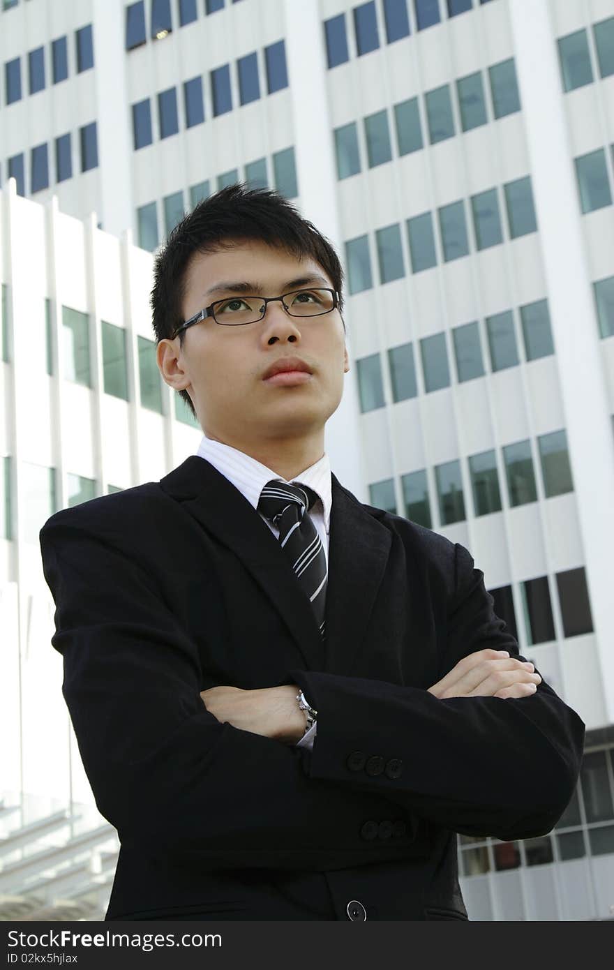 A young Asian businessman standing in front of an office building