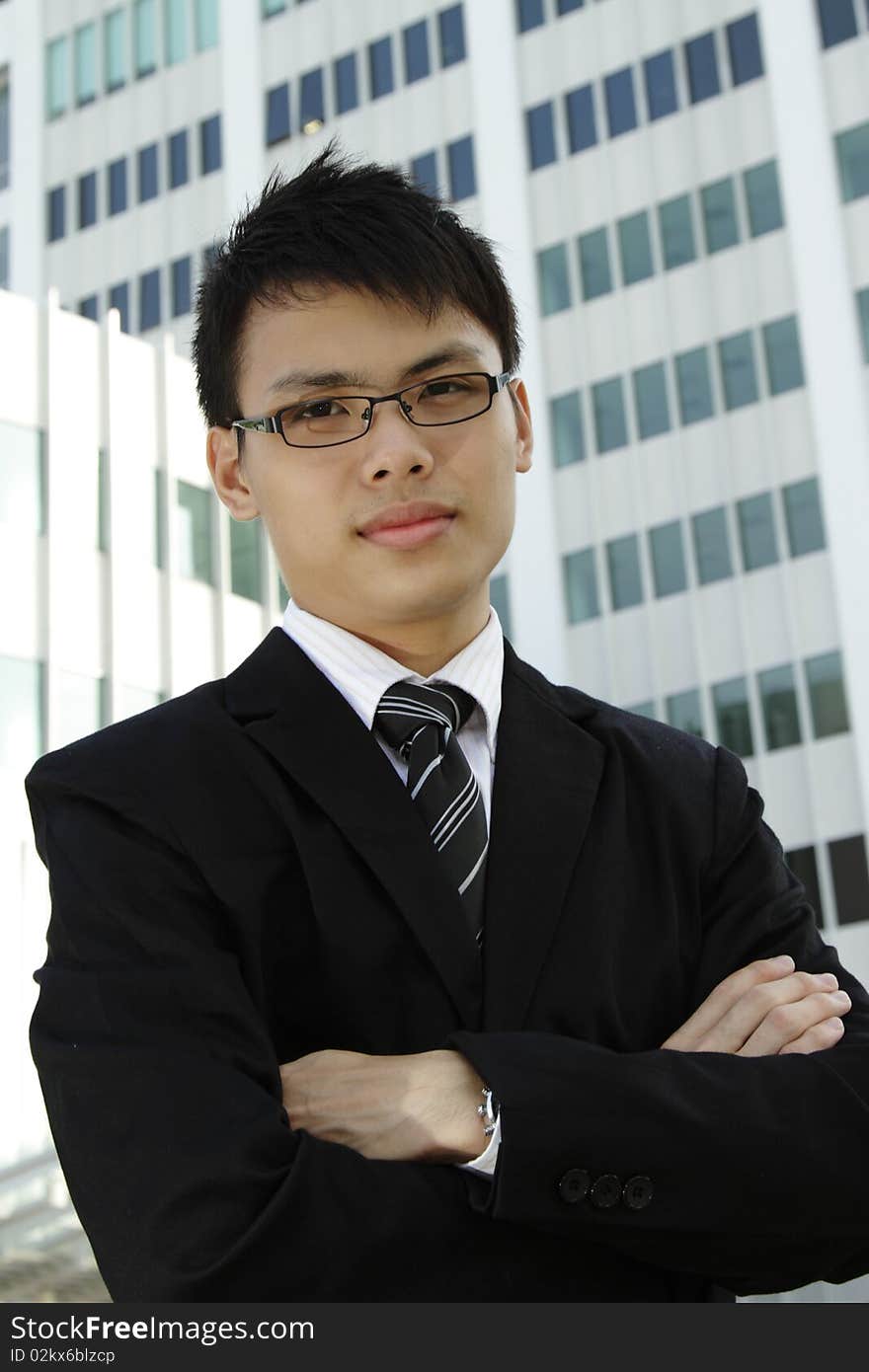 A young Asian businessman standing in front of an office building