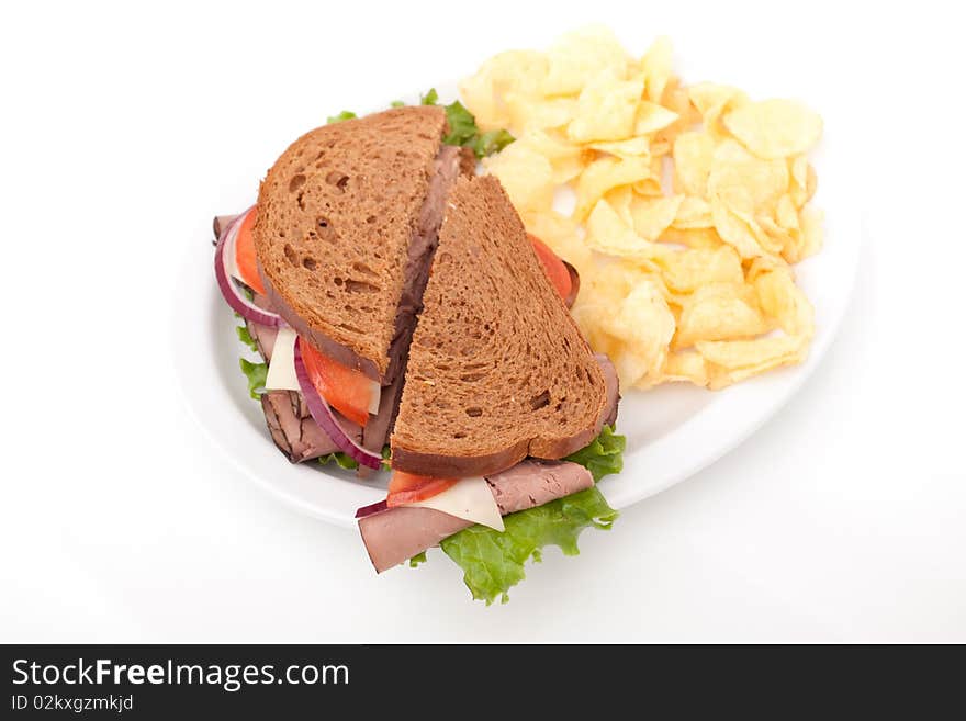 Delicious roast beef sandwich platter with whole wheat bread and potato chips. Delicious roast beef sandwich platter with whole wheat bread and potato chips