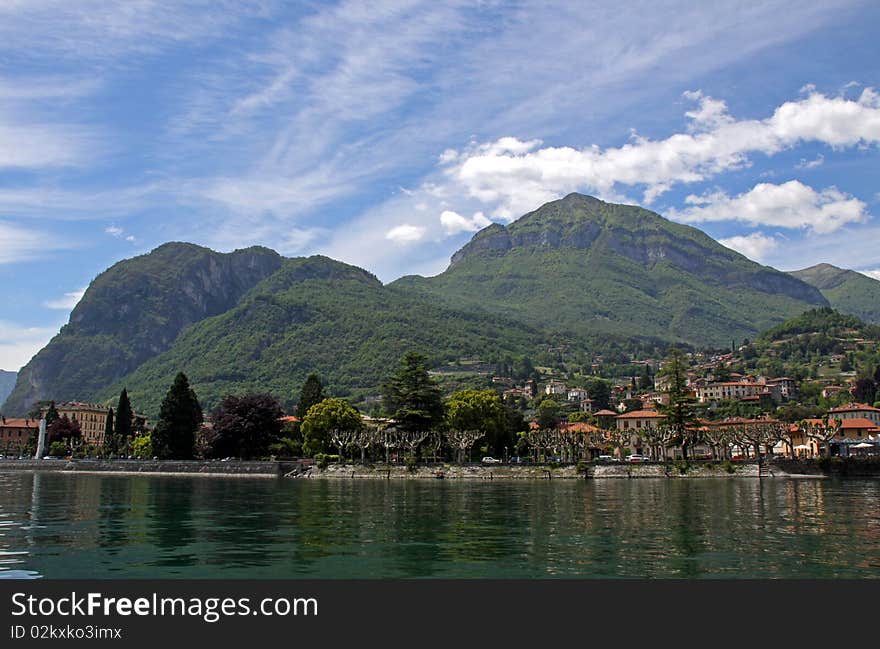 Scene of tree covered mountains and Lake Como in Italy with blue cloudy sky. Scene of tree covered mountains and Lake Como in Italy with blue cloudy sky