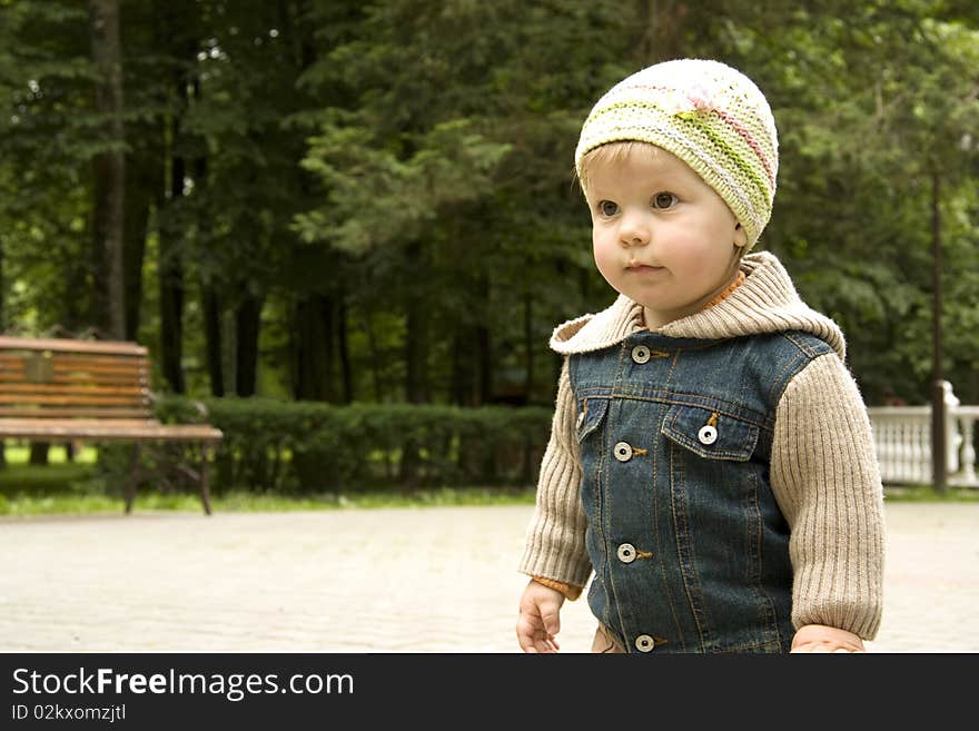 The child in a jeans jacket and a cap costs and looks forward. The child in a jeans jacket and a cap costs and looks forward