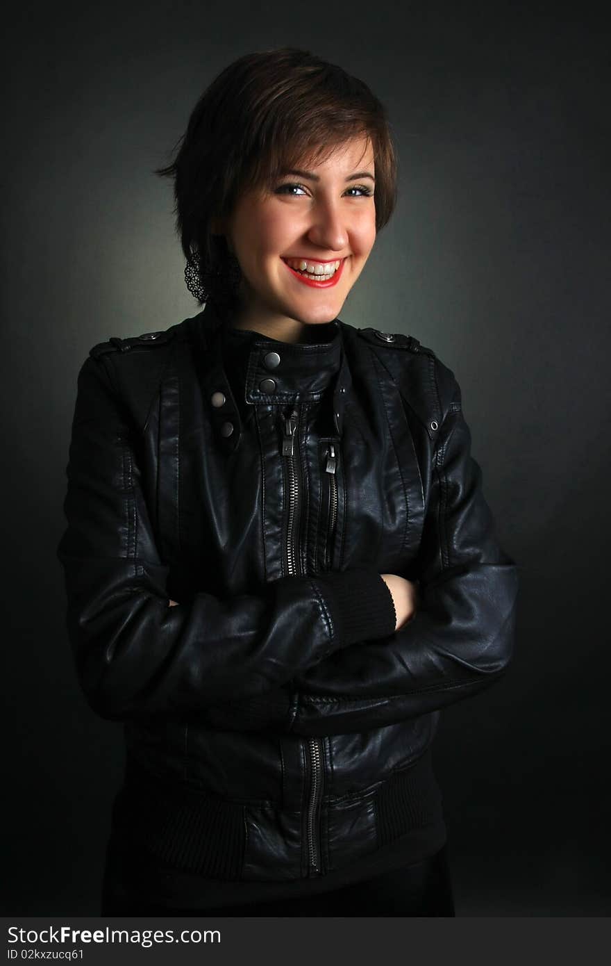 Rock girl in leather outfit smiling on black background