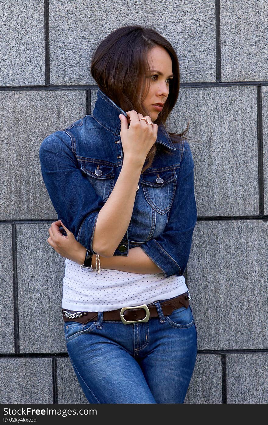 Young beautiful woman staying near the wall