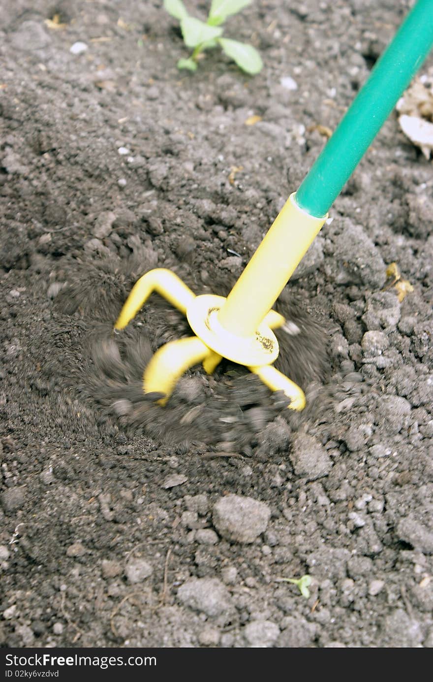 A closeup shot of a hand tiller working the dirt around with a motion blur to add effect.